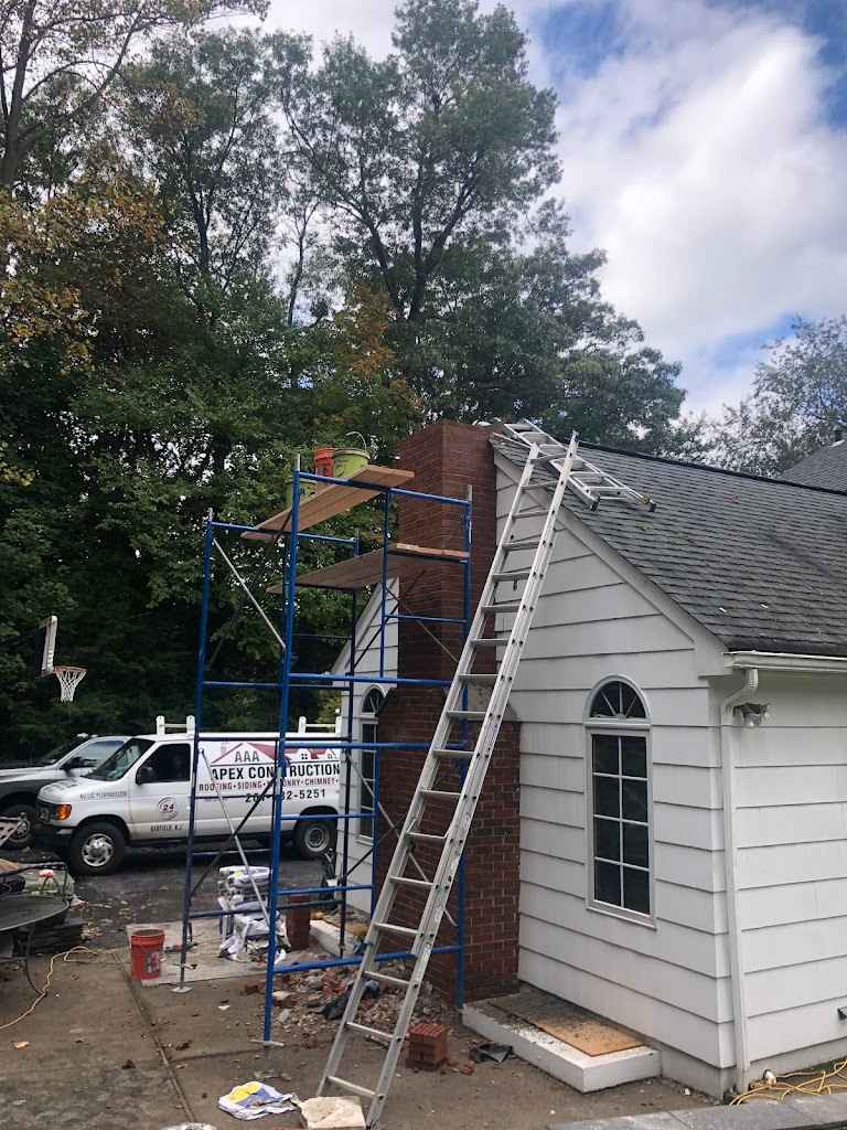 AAA Apex Construction van parked beside a house with scaffolding and a ladder set up at the chimney