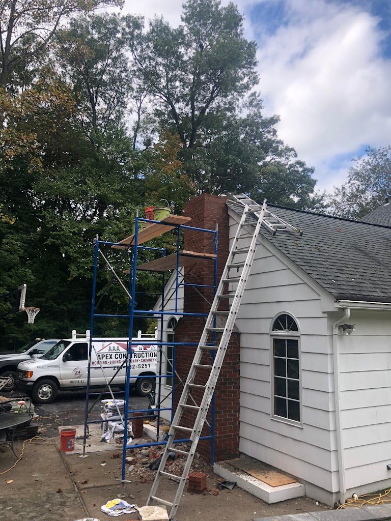 AAA Apex Construction van parked beside a house with scaffolding and a ladder set up at the chimney