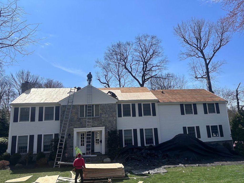 Two-story colonial home mid roof replacement with ladders, new plywood and protective tarps
