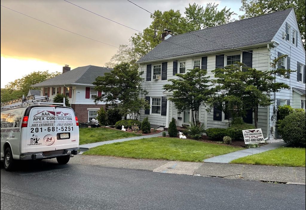 AAA Apex Construction van parked in front of a white colonial home with a company yard sign