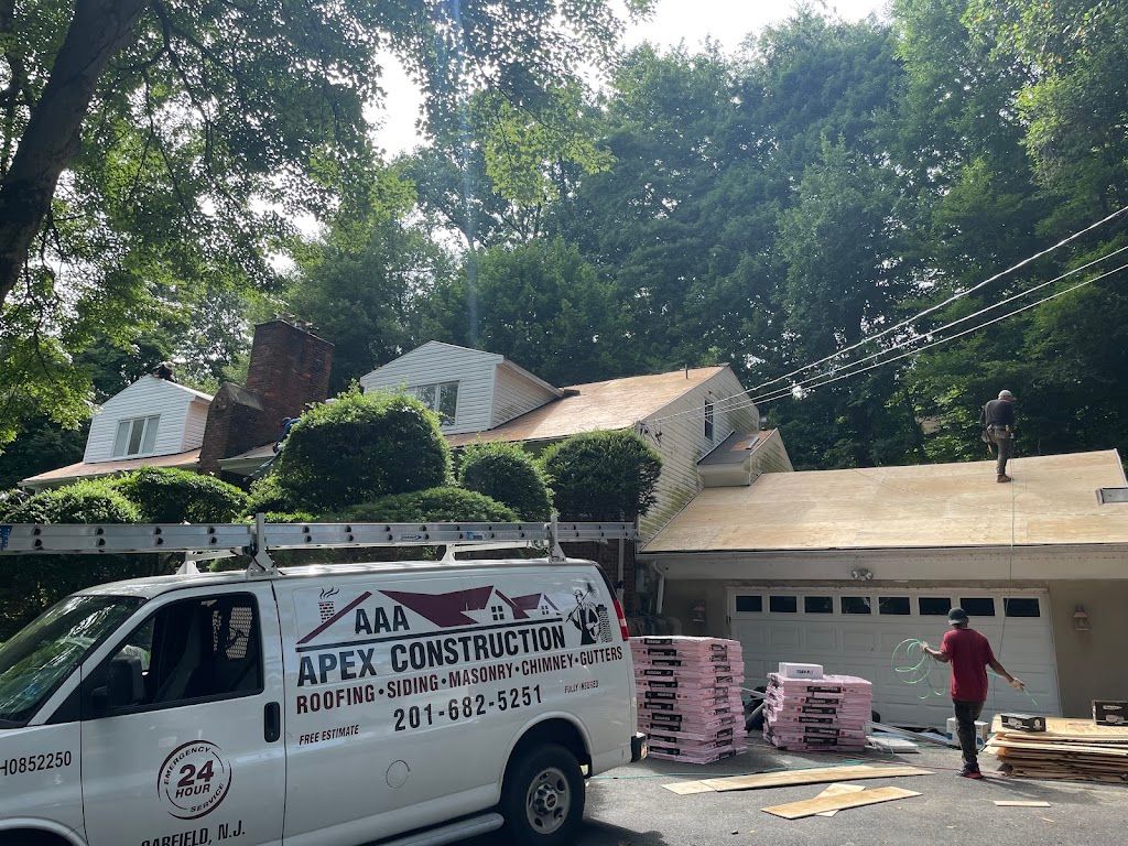 AAA Apex Construction van parked at a job with bundles of shingles staged in the driveway